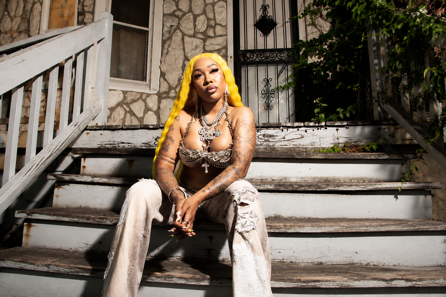 Glizzy Glow, Chicago rapper, seated on porch steps — Trench Baddie press cycle