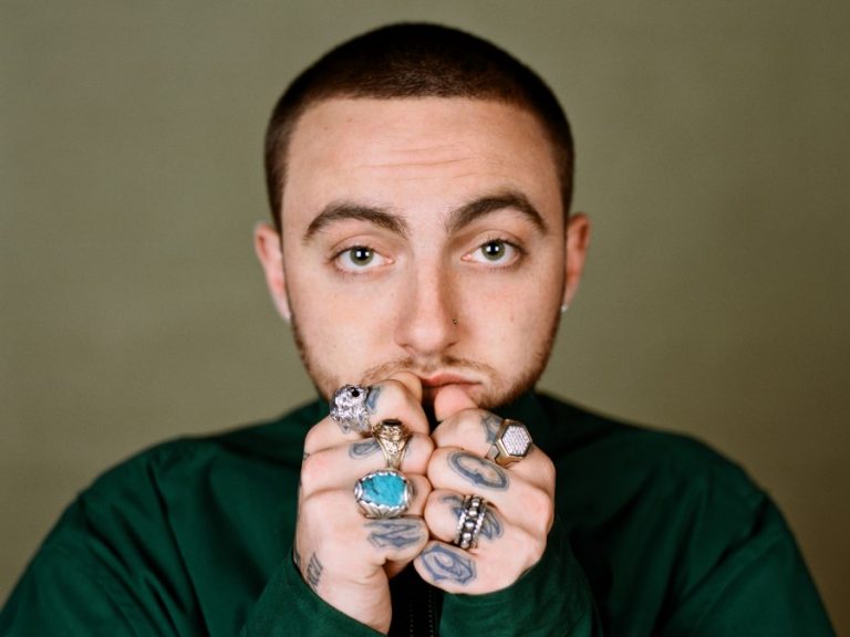 Mac Miller in a green shirt with ring-covered hands near his face